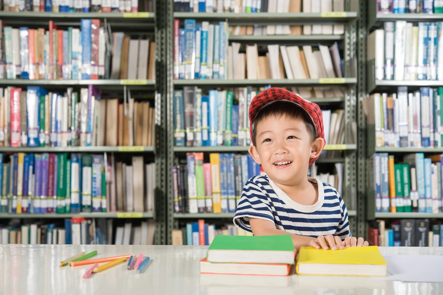 Smiling boy in red cap in library