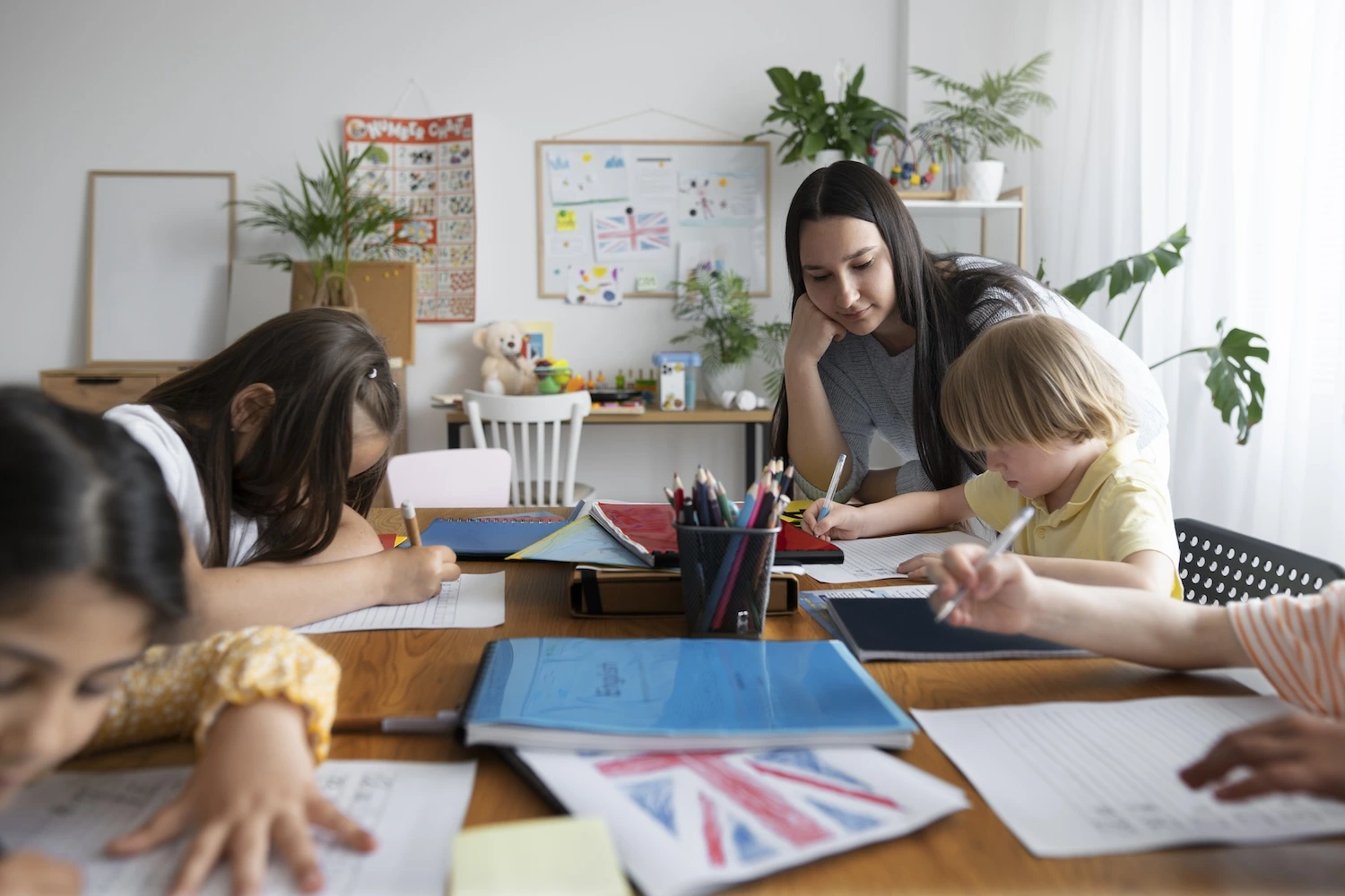 Four students writing in a class room with a teacher