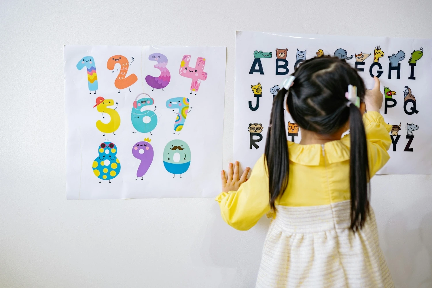 A girl in yellow dress learning alphabets