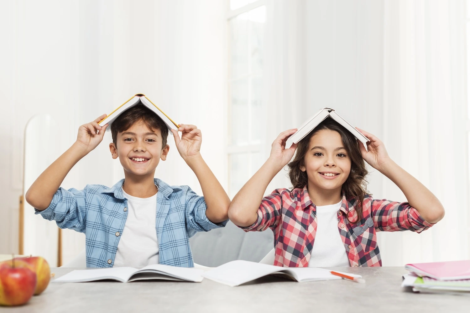 Two boys holding a book over their heads and smiling
